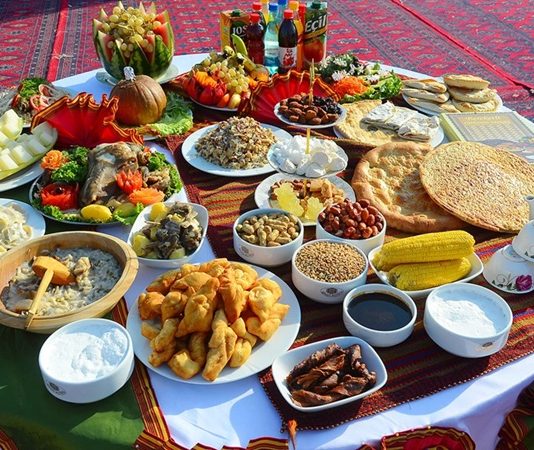 Türkmenistan Mutfağı Türkmenistan mutfağı, Orta Asya’nın kurak ve çöl bölgelerinde göçebe yaşam tarzının etkisiyle şekillenmiş, hem pratik hem de besleyici yemeklerle öne çıkan bir mutfaktır. Tarih boyunca hayvancılık, tarım ve baharat kullanımı mutfağın temelini oluşturmuştur. Et ve tahıllar günlük beslenmenin başlıca öğeleri iken, sebzeler ve baharatlar yemeklere zengin bir tat ve aroma kazandırır. Konulu bir haber görseli.