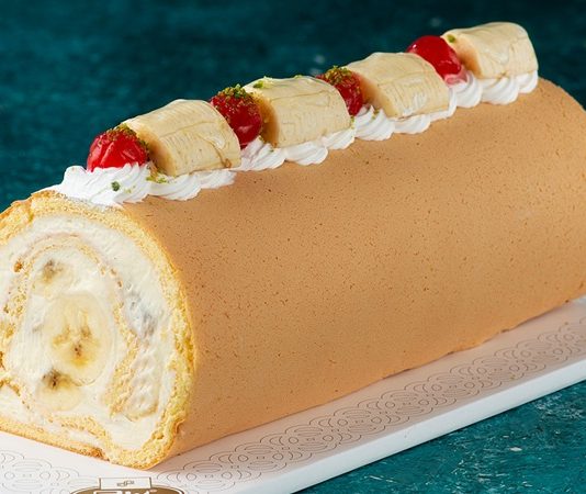 Muzlu Rulo Pasta Lezzetiyle Sofraların Yeni Gözdesi Ev yapımı tatlılara olan ilgi her geçen gün artarken, hem pratik hazırlanışı hem de hafif yapısıyla muzlu rulo pasta yeniden gündemin üst sıralarına çıkıyor. Özellikle evde yapılan pastalara yönelimin arttığı bu dönemde, klasik yaş pastalara alternatif olarak görülen bu tatlı, hem sunumuyla hem de lezzetiyle dikkat çekiyor. Yumuşak pandispanya dokusu, muzun doğal aroması ve hafif kremasıyla öne çıkan muzlu rulo pasta, çay saatlerinden özel davetlere kadar geniş bir kullanım alanına sahip. Konulu bir haber görseli.