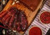 Kuru Et ve Pastırma Geleneksel Lezzetlerin Sofralardaki Gücü Kuru et ve pastırma, yüzyıllardır farklı coğrafyalarda tüketilen ve özellikle Anadolu mutfağında önemli bir yere sahip olan geleneksel et ürünleri arasında bulunuyor. Dayanıklılığı, yoğun aroması ve uzun süre saklanabilme özelliği sayesinde kuru et ve pastırma, hem geçmişte hem de günümüzde sofraların vazgeçilmezleri arasında yer alıyor. Modern üretim teknikleri gelişmiş olsa da bu ürünlerin temelinde hâlâ geleneksel yöntemler ve ustalık bilgisi bulunuyor. Konulu bir haber görseli.