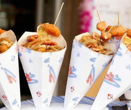 Şehrin Ritmini Taşıyan Sokak Yemekleri Standları Kültürü Sokak yemekleri standları, şehir yaşamının en canlı ve en erişilebilir gastronomi alanlarından biri olarak kabul ediliyor. Günün her saatinde farklı kesimlerden insanları bir araya getiren bu alanlar, yalnızca hızlı ve uygun fiyatlı yiyecekler sunmakla kalmıyor, aynı zamanda kentin kültürel dokusunu da yansıtıyor. Sokak yemekleri, geçmişten bugüne hem ekonomik hem de sosyal yönleriyle önemli bir yer tutarken, günümüzde gastronomi turizminin de vazgeçilmez parçalarından biri hâline gelmiş durumda. Konulu bir haber görseli.